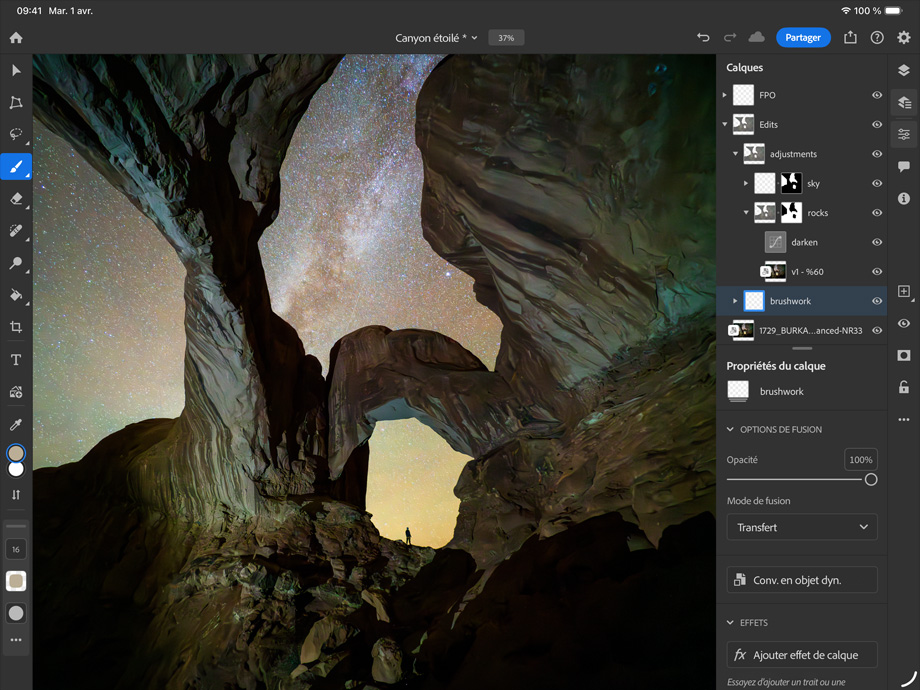 Un iPad Pro, face avant, orientation paysage, noir infini, coins arrondis, bordure d’écran noire, écran affichant une photo en cours de retouche d’un canyon et d’un ciel étoilé, sur la droite, des calques, des outils et des effets de retouche sont visibles, y compris les pinceaux, les ajustements et d’autres