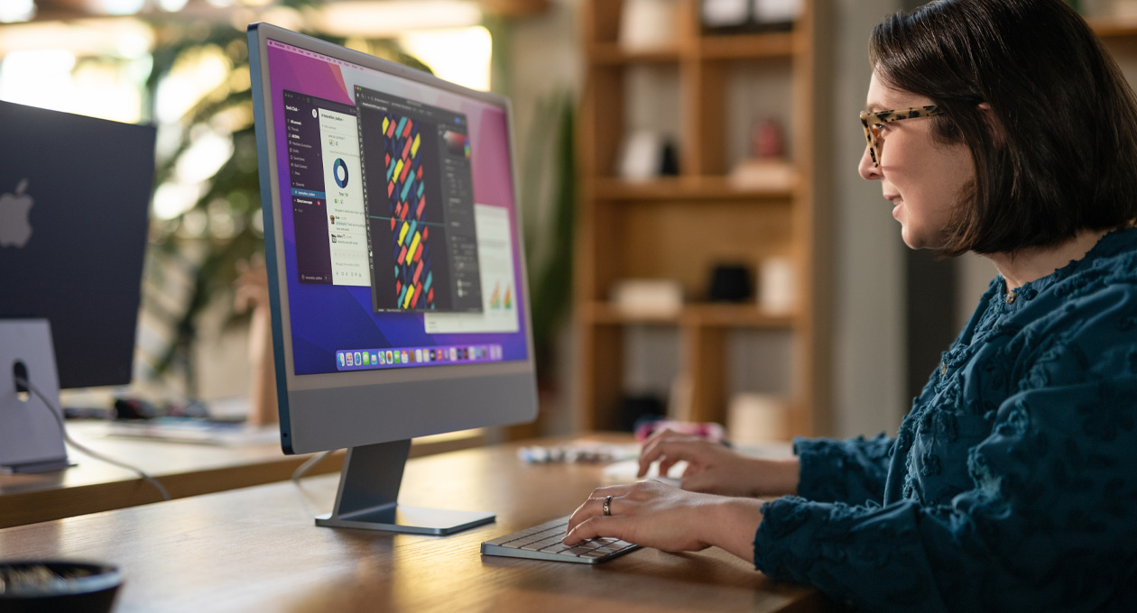 一個人在辦公環境中使用 iMac 工作，螢幕顯示色彩繽紛的設計 app